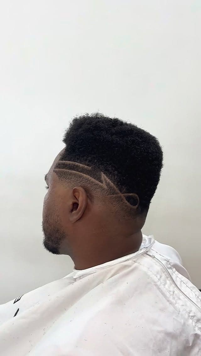 Corte afro com degradê e desenho freestyle feito por Cris Barber